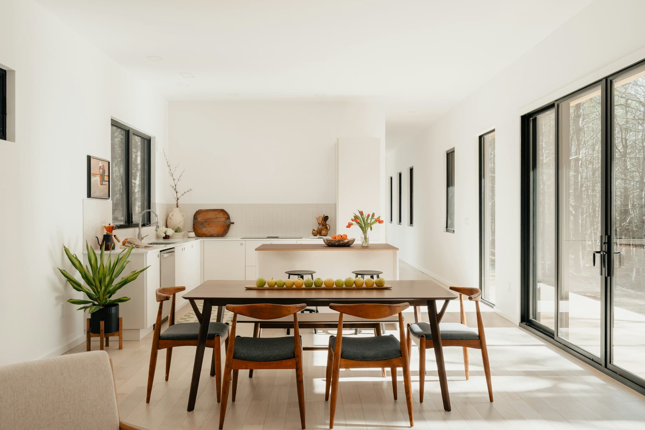 Dining table with wooden chairs in a bright open-plan room with garden doors