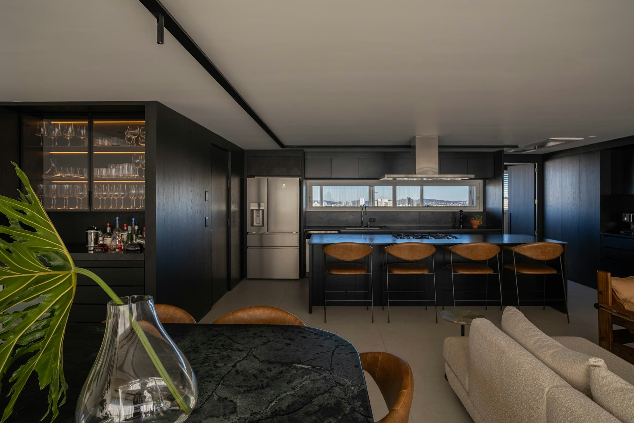 Kitchen with dark cabinetry, a long island and leather bar stools
