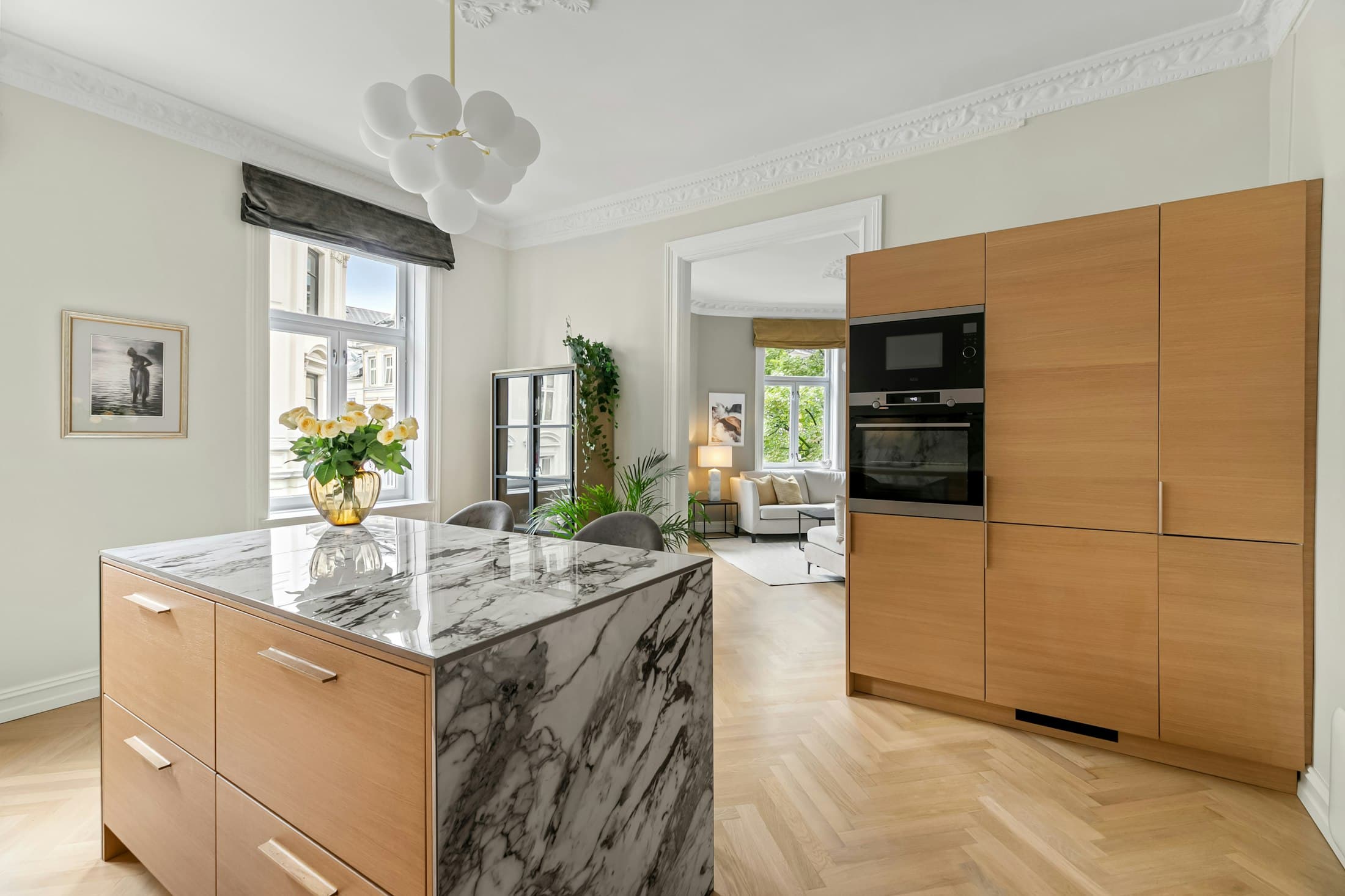 Kitchen with a veined marble island, warm timber cabinetry and herringbone flooring
