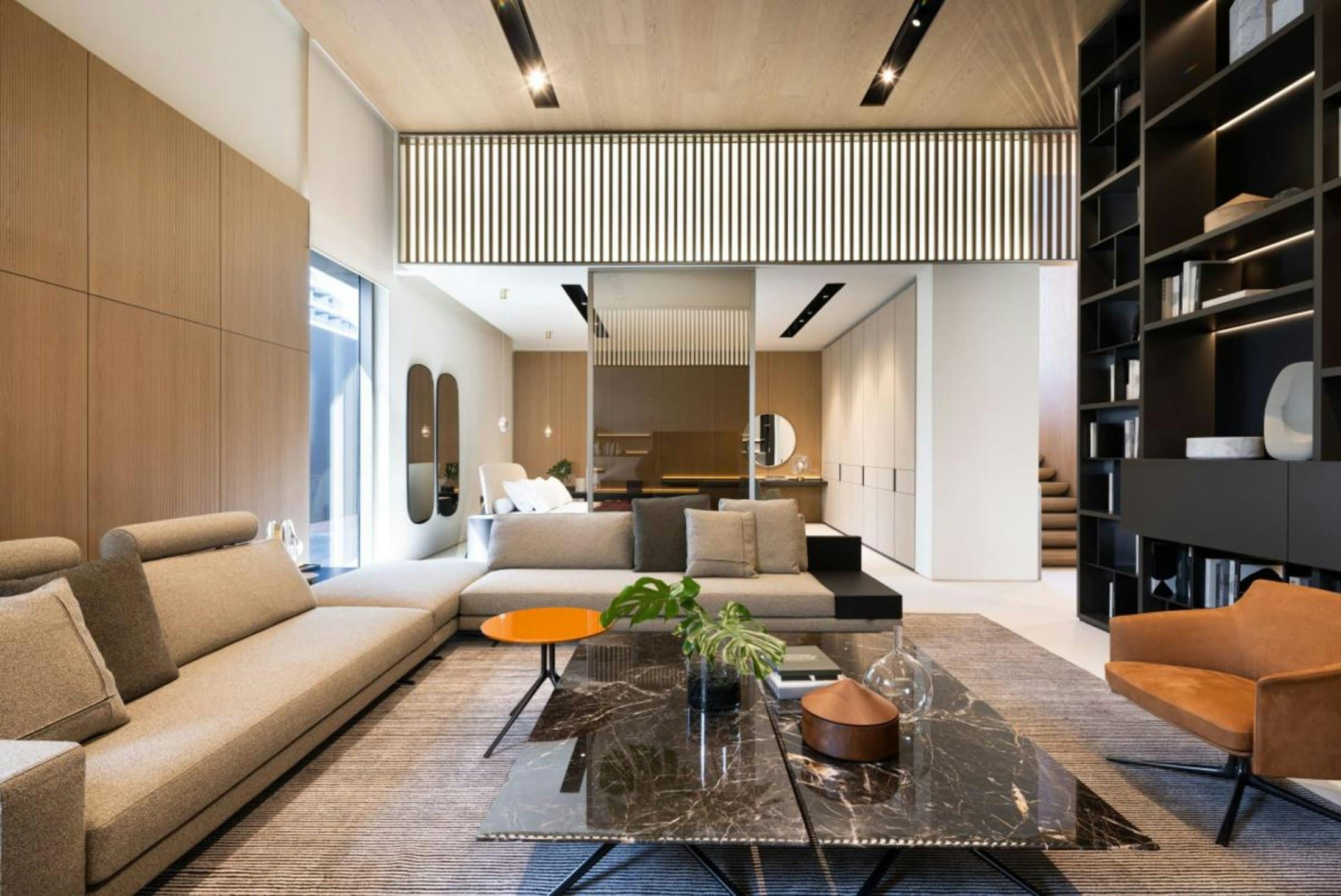 Open-plan living area with a sectional sofa, timber joinery and built-in bookshelves