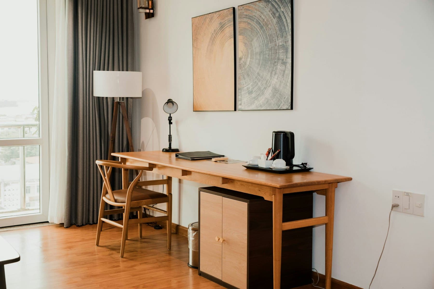 Home study with a solid wood desk, wishbone chair and floor lamp by a window