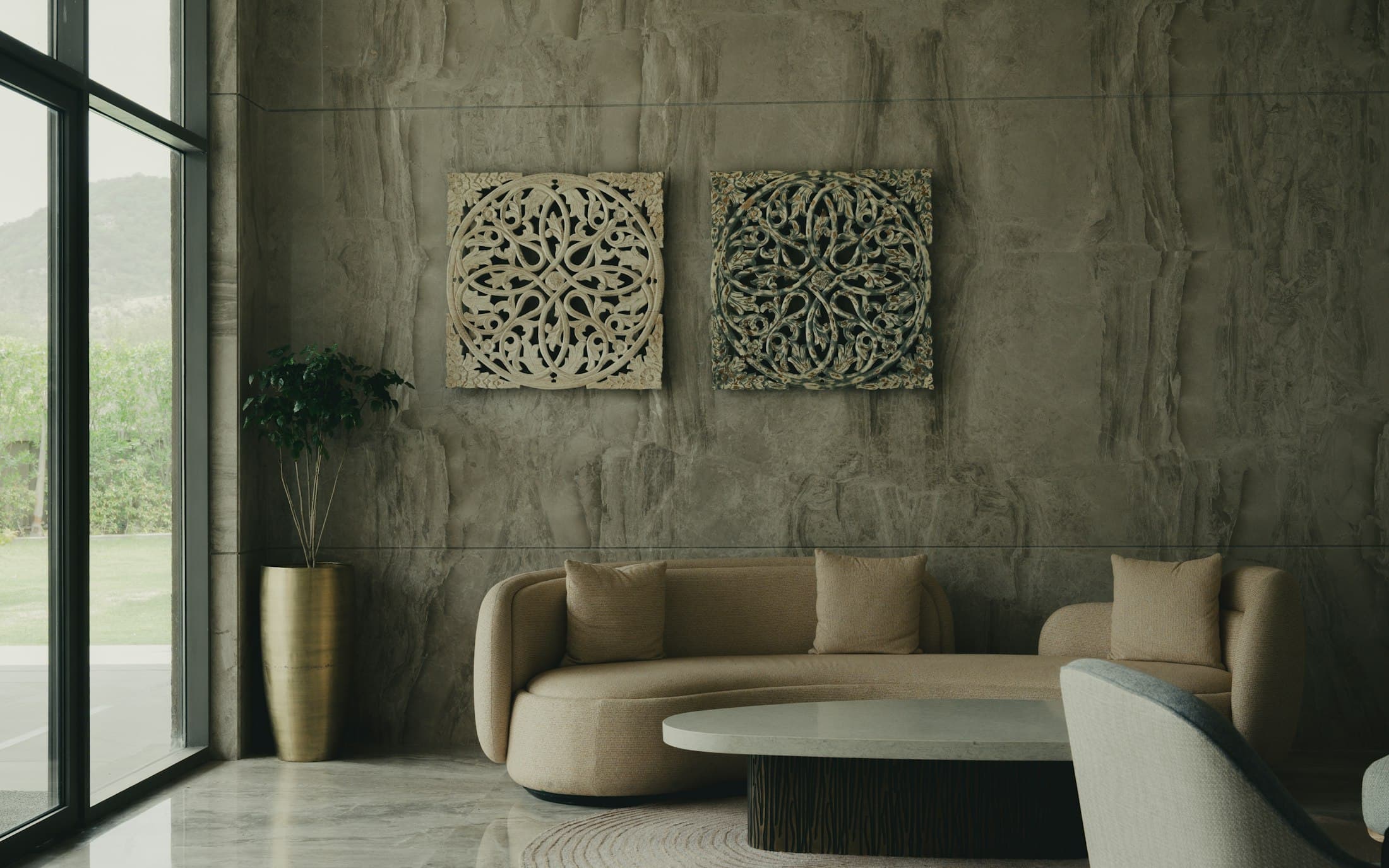 Curved bouclé sofa against a textured plaster wall with carved wooden wall art
